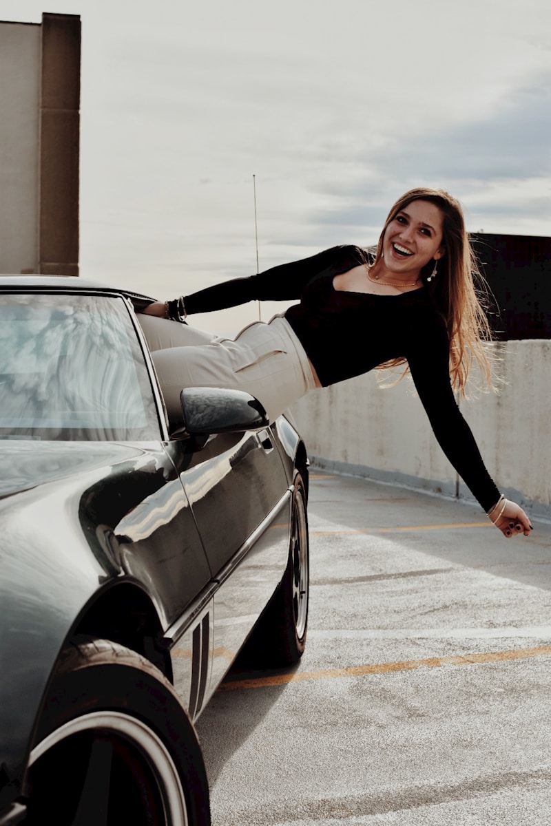 a young woman with auto insurance for teenagers leaning on the hood of a car